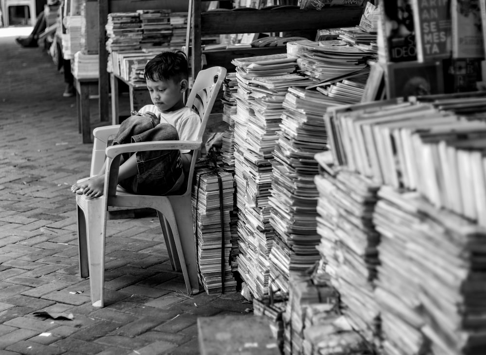 boy sitting on chair beside papers