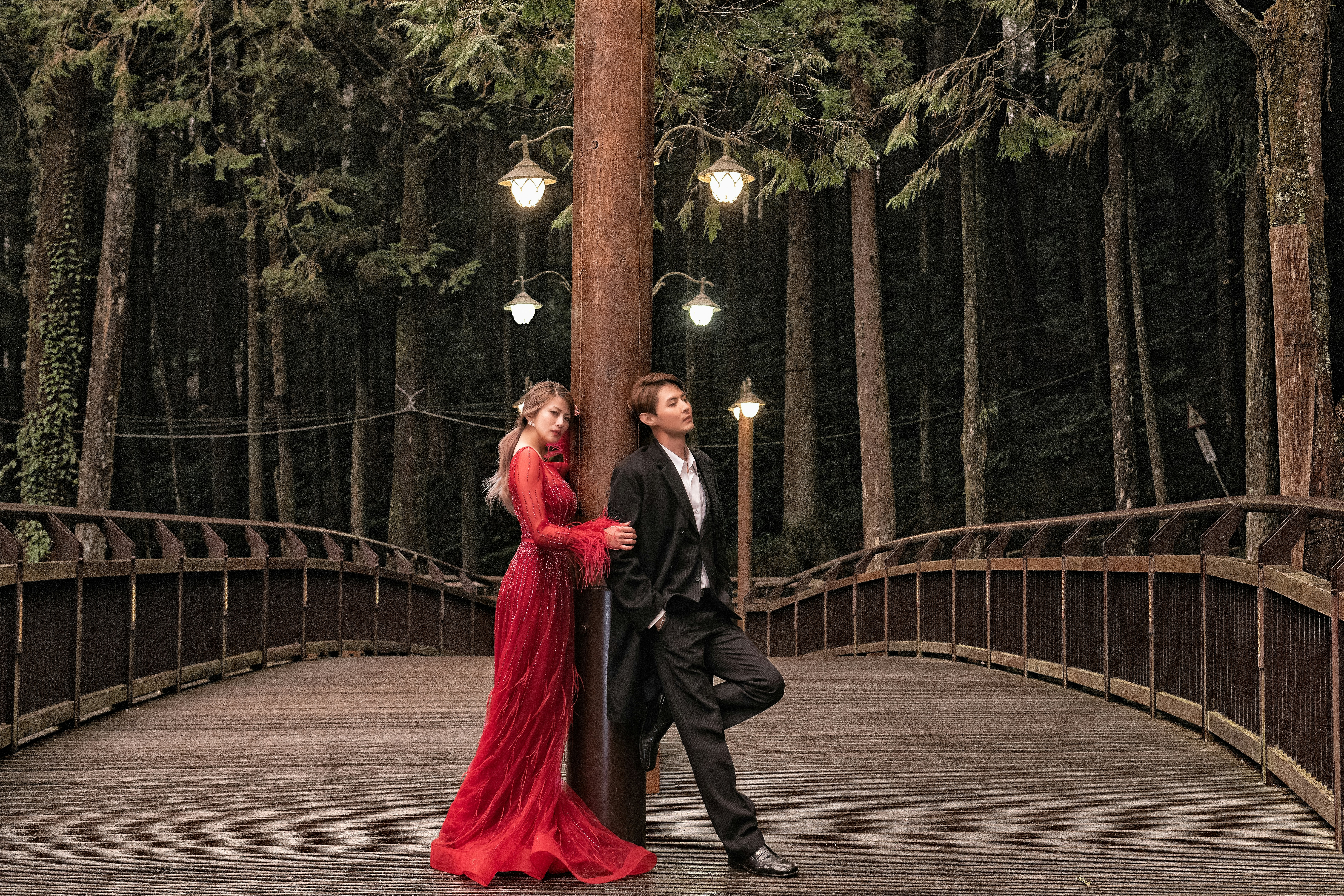 woman in red gown standing behind man in black tuzedo