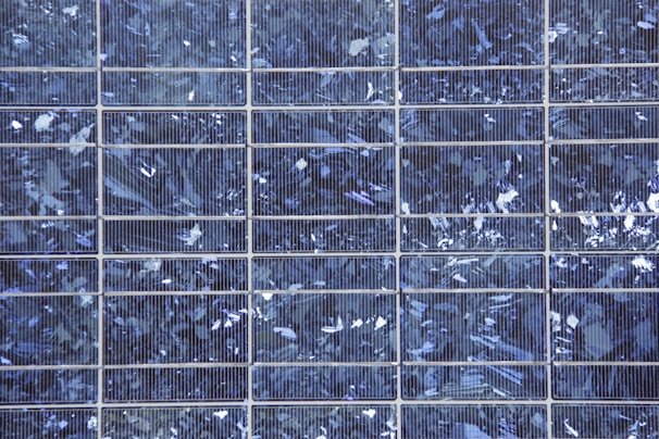 Close-up of solar panels capturing sunlight with a hint of blue and green hues reflecting off the surface