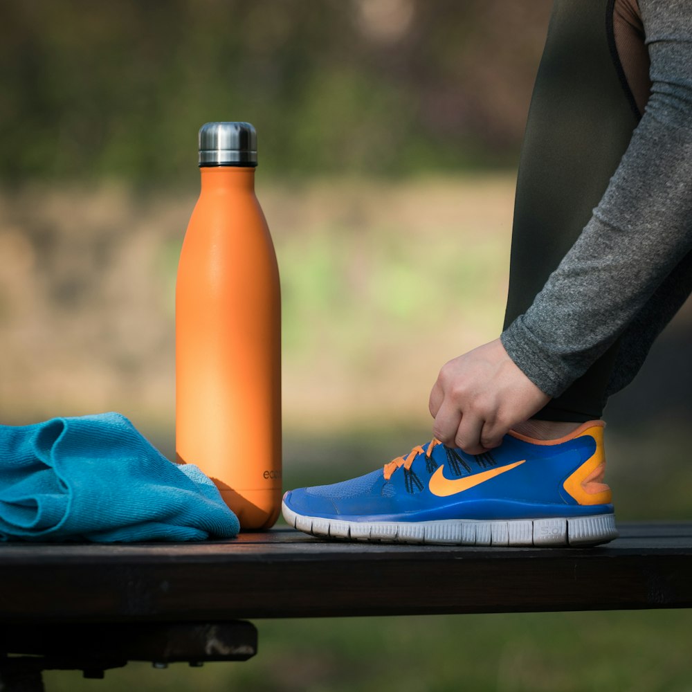 woman fixing her shoe lace while stepping on bench