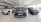 A sleek and modern car showroom featuring a line of luxury SUVs. The vehicles are displayed on a glossy white tiled floor under bright lighting, which enhances their metallic finishes. The cars are positioned in a spacious and well-lit environment, possibly indicating a high-end automobile dealership.