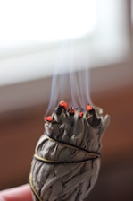 A serene setting with sage smoke swirling in the air, symbolizing a cleansing ritual.