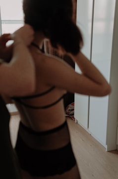 Minimalist editorial photo of a model wearing layered digital fashion pieces in a dark room.