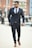 Close-up of a man confidently walking down a city street in trendy menswear.