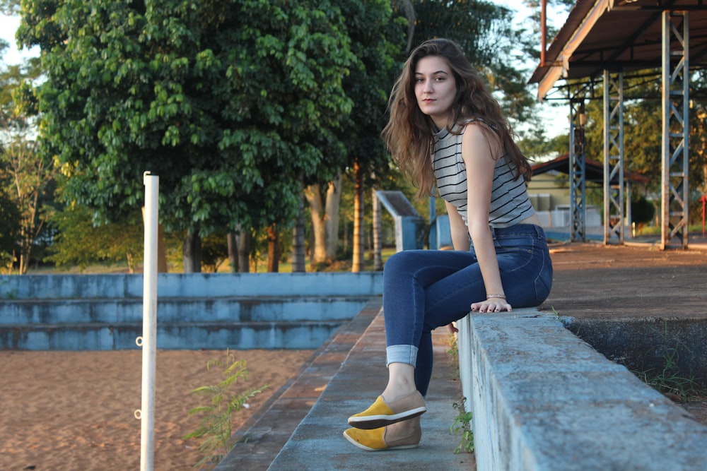 mulher sentada na superfície de concreto durante o dia