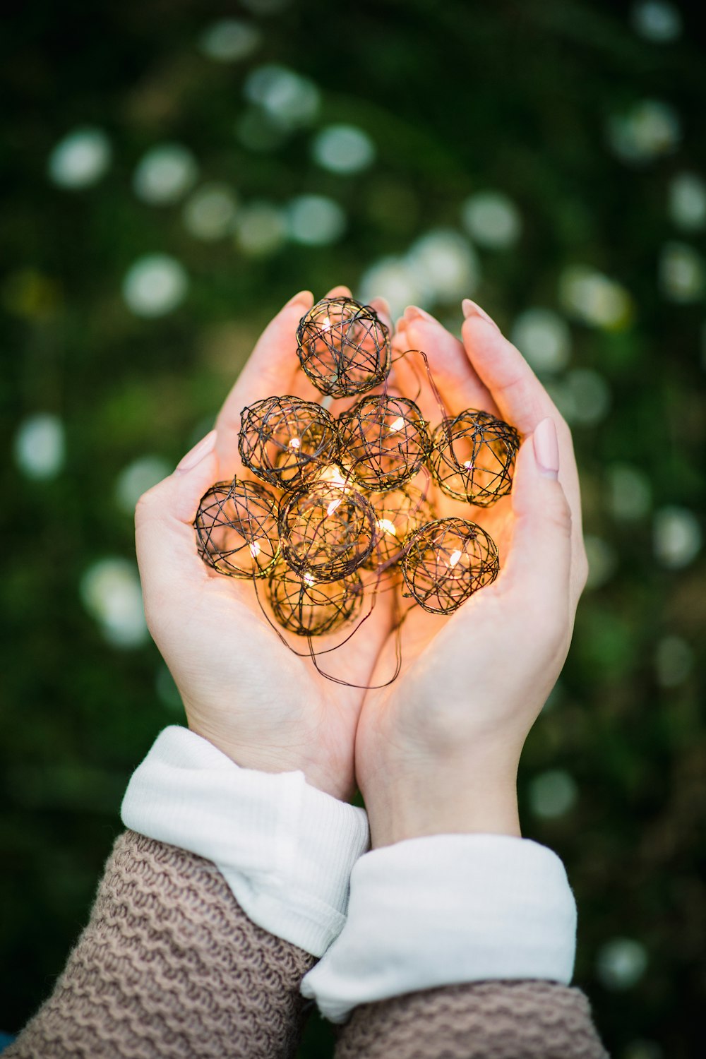 black lighted ball ornaments on woman's palms