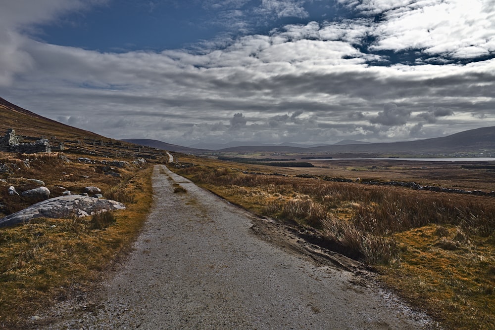 empty dirt road under clouds