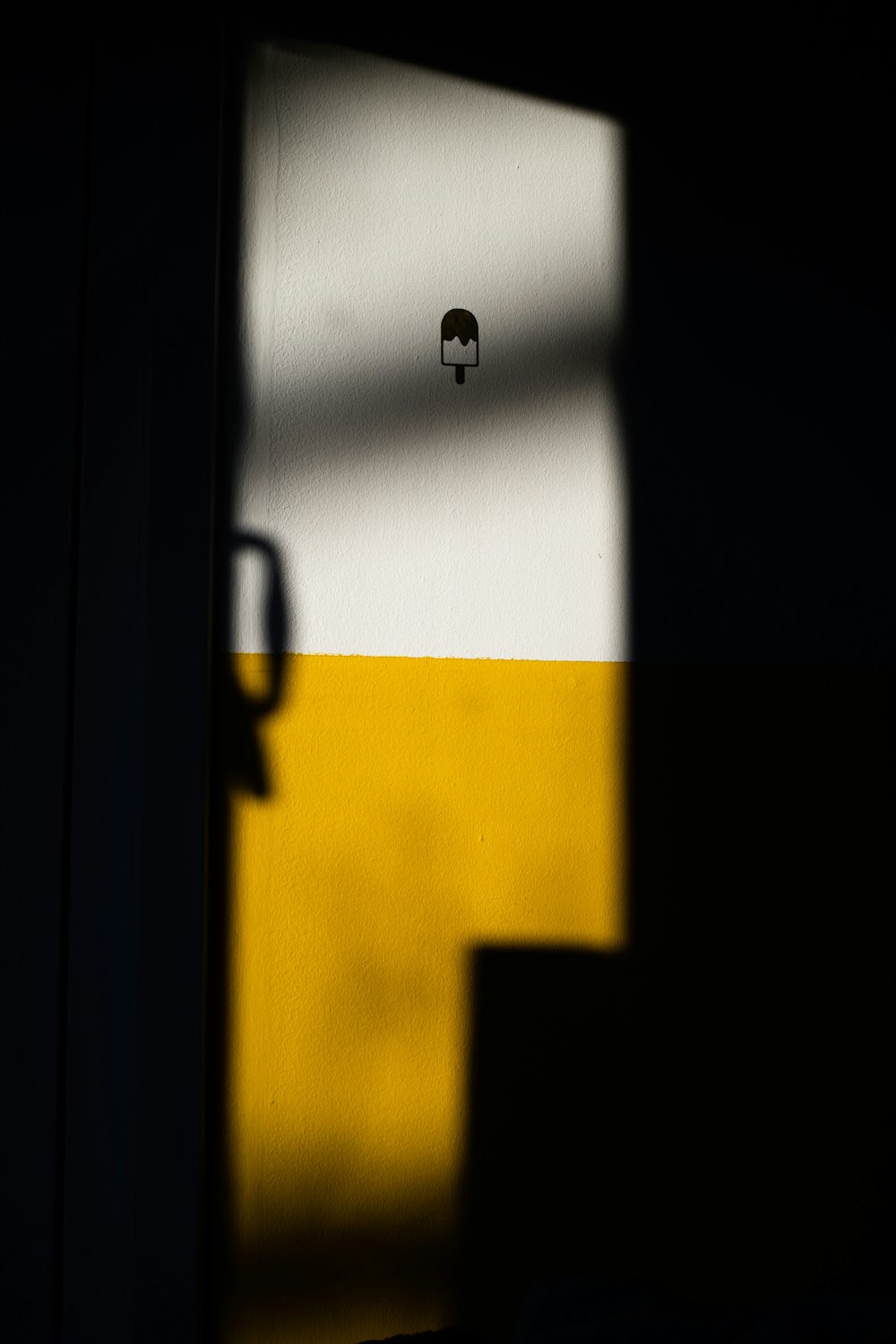 a shadow of an elephant on a yellow and white wall