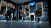 A stylish barber chair in front of a modern mirror reflecting the barbershop’s ambient lighting.