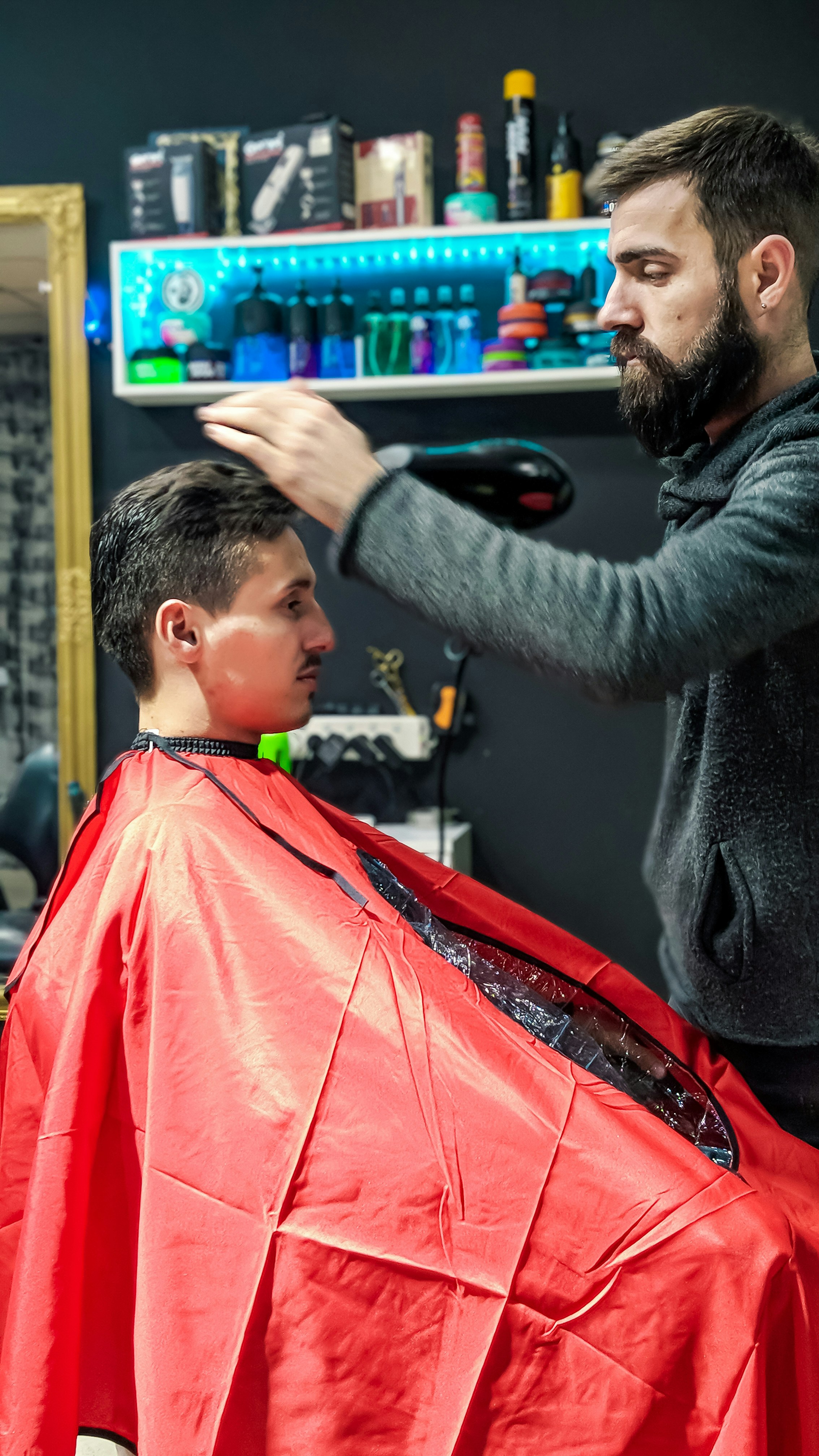 Barber giving classic scissor haircut, bright salon lighting, clean white cape