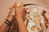Hands decorating a vanilla cake with colorful sprinkles in a cozy kitchen