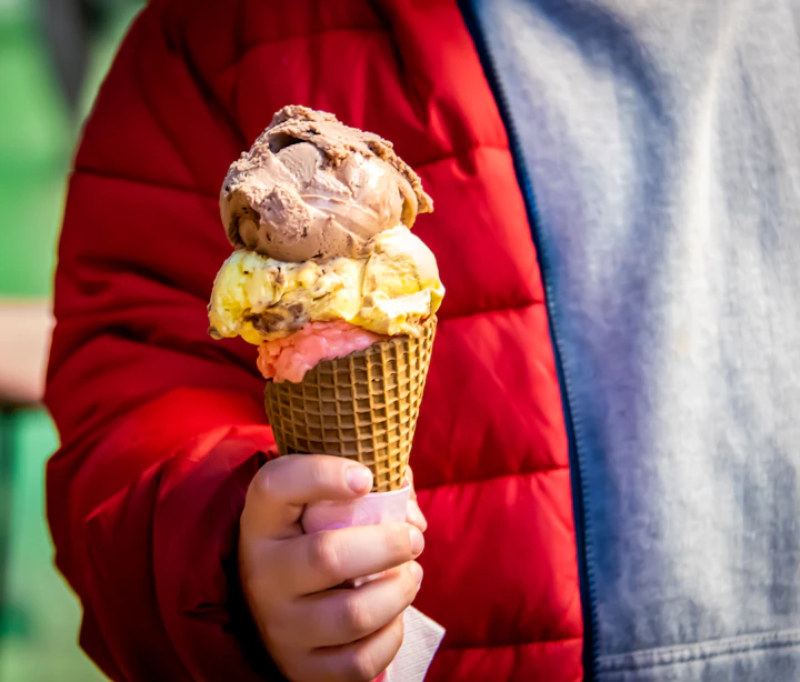 A colorful triple-scoop ice cream cone held up in a hand