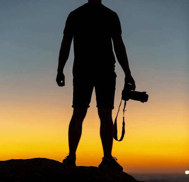 silhouette of man standing on cliff