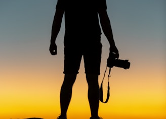 silhouette of man standing on cliff