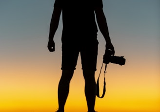 silhouette of man standing on cliff