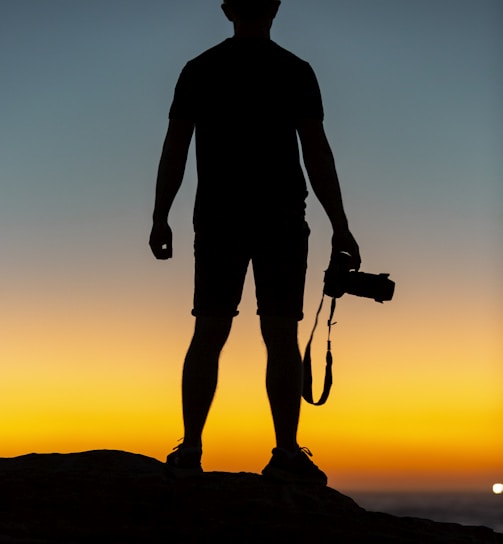 silhouette of man standing on cliff