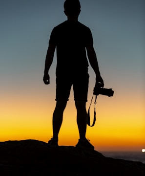 silhouette of man standing on cliff