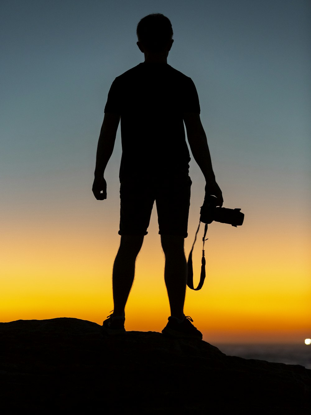 Silhouette eines Mannes, der auf einer Klippe steht