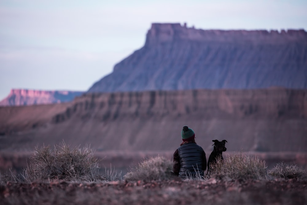 woman sitting in the middle of the field beside dog