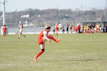 Close-up of a player wearing a bright team jersey, mid-kick with a blurred stadium background