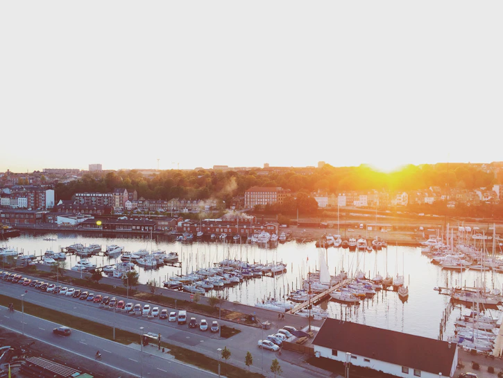 A vibrant marina at sunset with boats docked and people enjoying the waterfront.