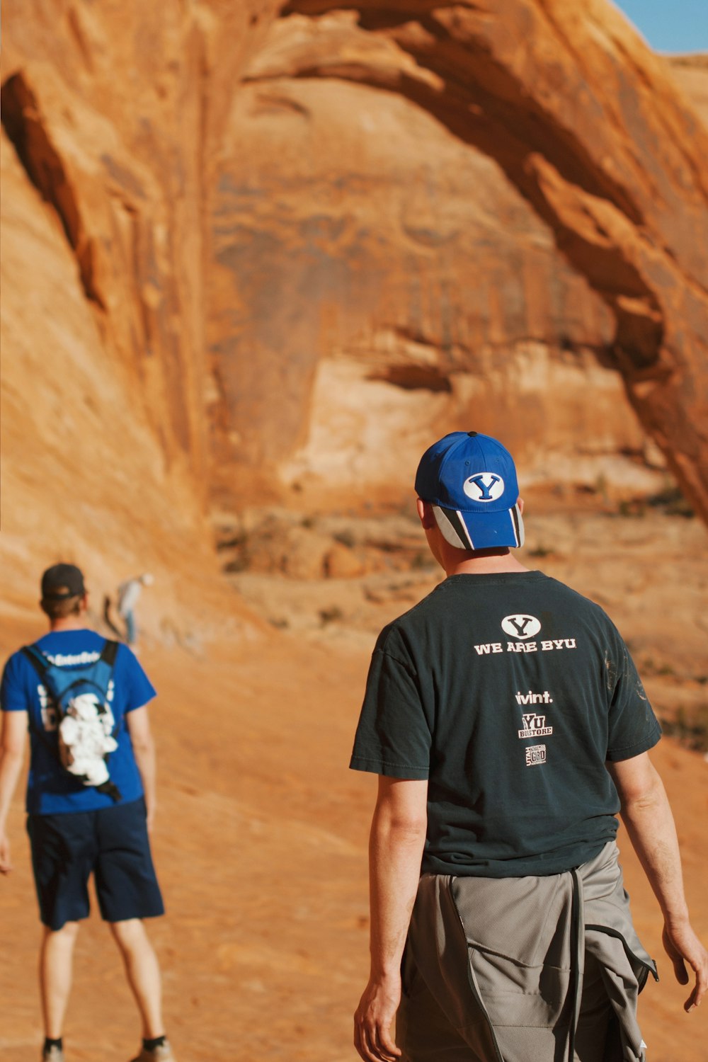 man in black t-shirt standing near rock formation