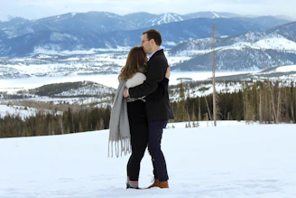 Snow-capped mountains framing a couple enjoying a cozy bonfire.