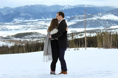 Snow-capped mountains framing a couple enjoying a cozy bonfire.
