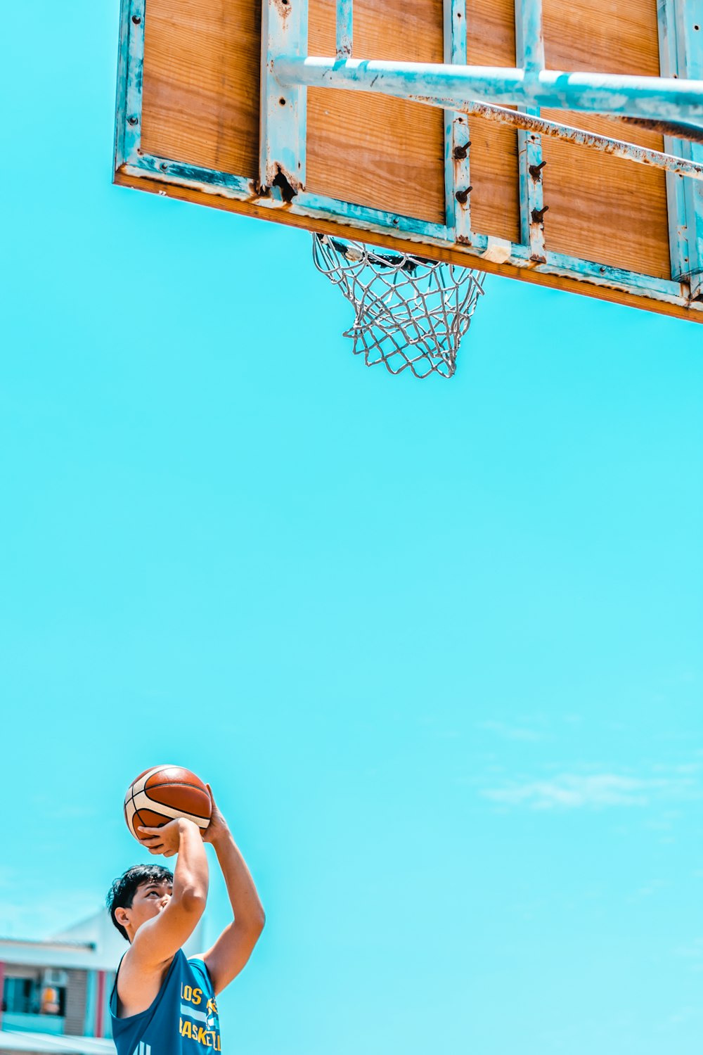 man holding basketball in front of basketball system during daytime