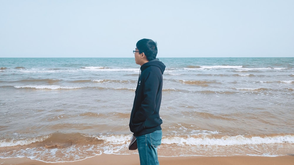 man in black hoodie standing on shore