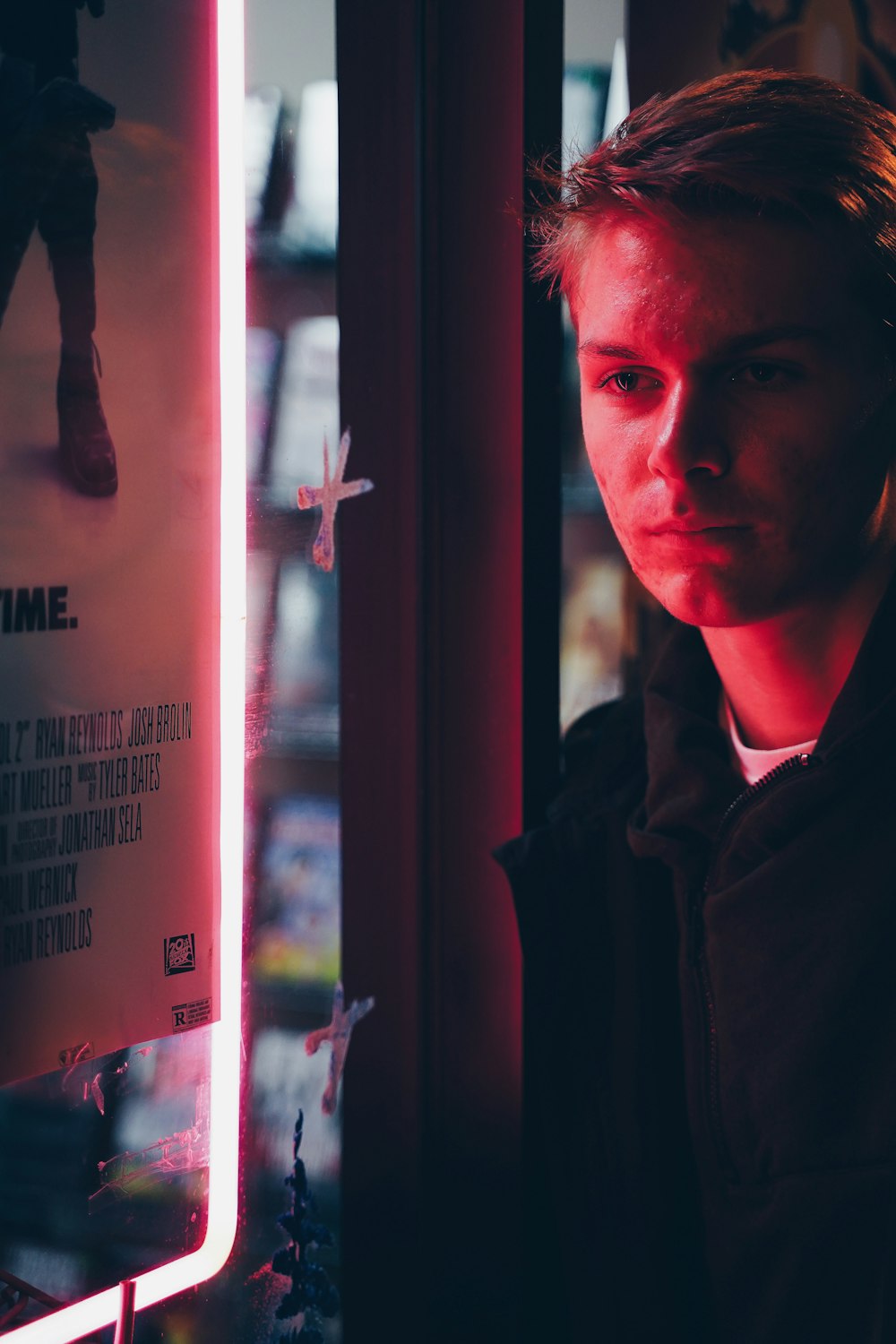 man wearing black coat standing near glass window