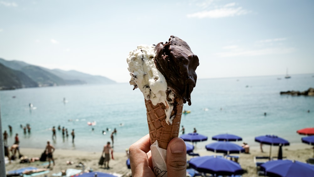 person holding ice cream front of sea at daytime