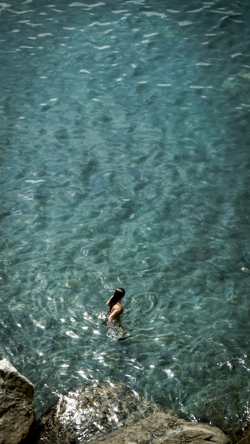 aerial photo of woman swimming on clear water