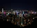A dynamic nighttime view of Hong Kong’s skyline glowing with sunset yellow and orange lights reflecting on the harbor.