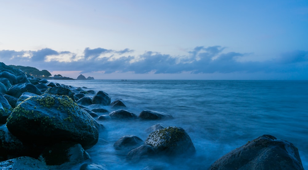 rocks near calm sea under blue sky