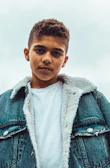 boy wearing blue denim jacket standing and looking straight