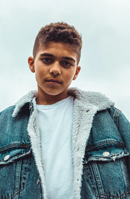 boy wearing blue denim jacket standing and looking straight