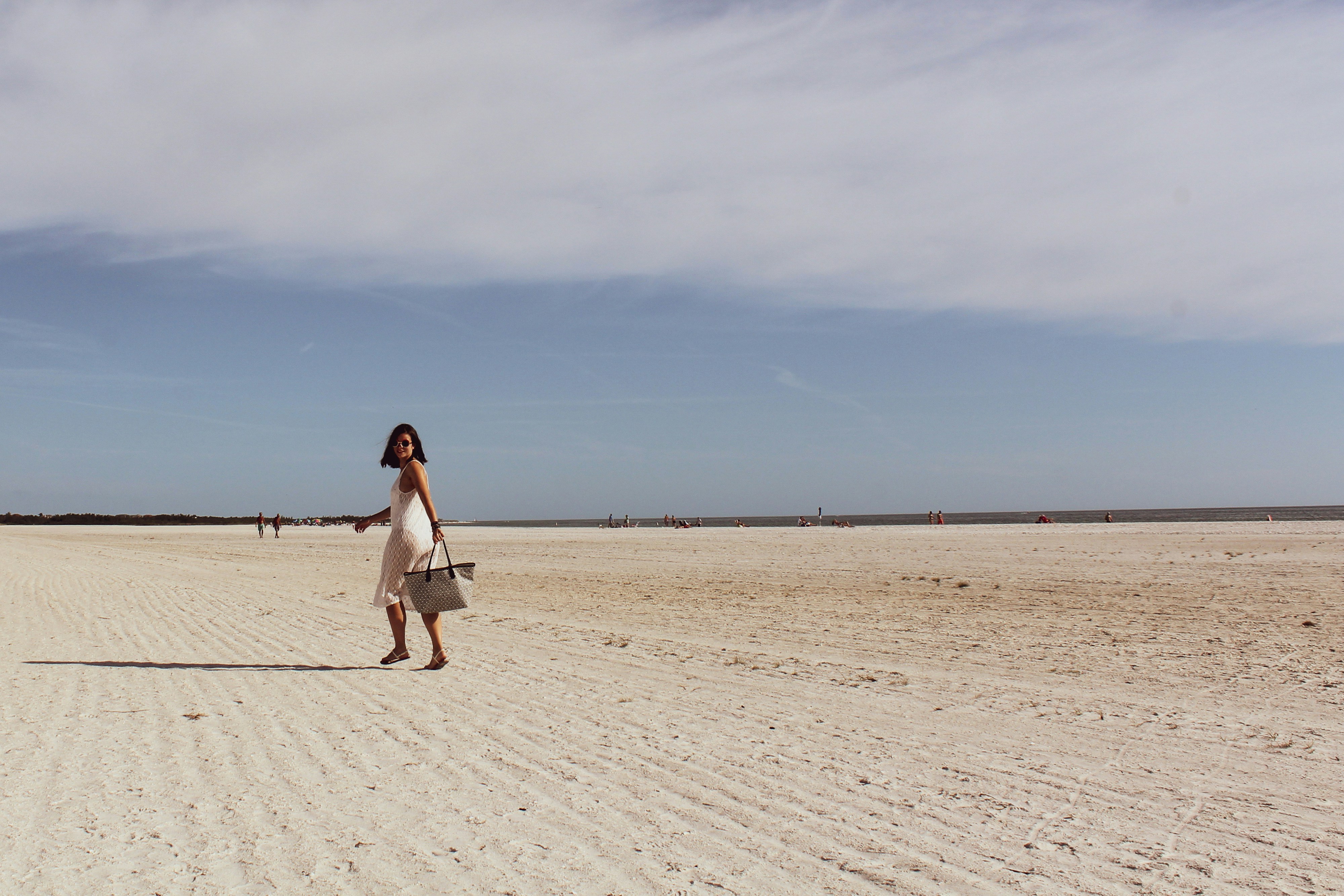woman in white dress walking on sand during daytime, 