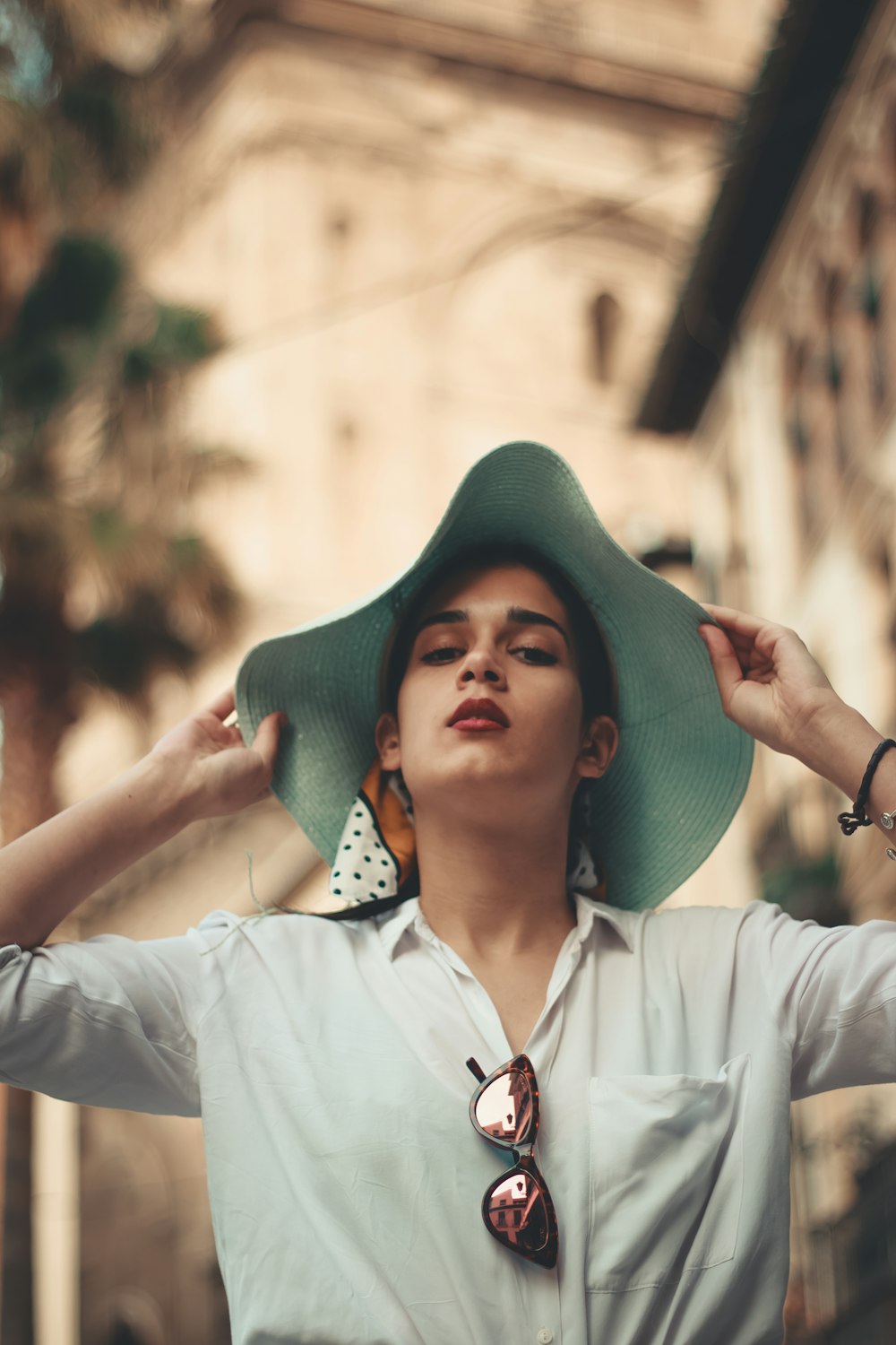 woman in white button-up long-sleeved shirt holding blue hat