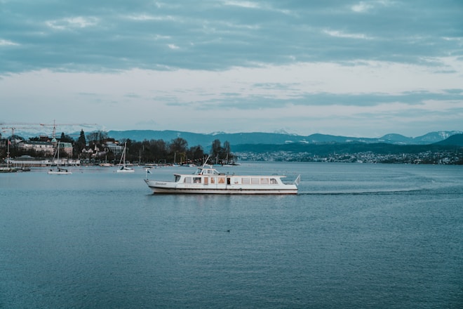 white boat on calm sea under white sky during day time