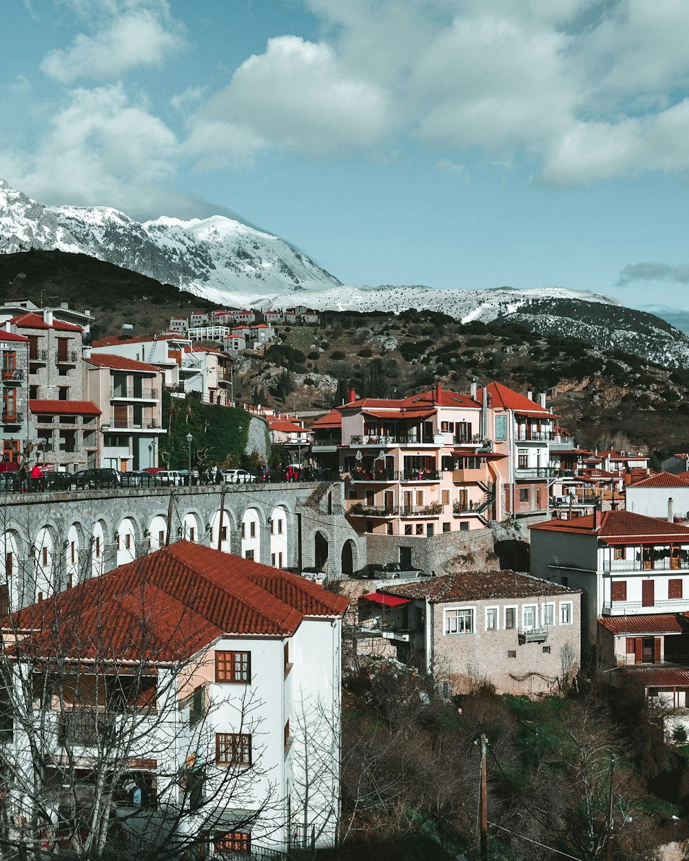 white and brown concrete houses viewing mountain covered with snow under white and blue skies