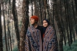 man and woman in one blanket under the woods
