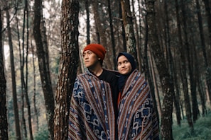 man and woman in one blanket under the woods