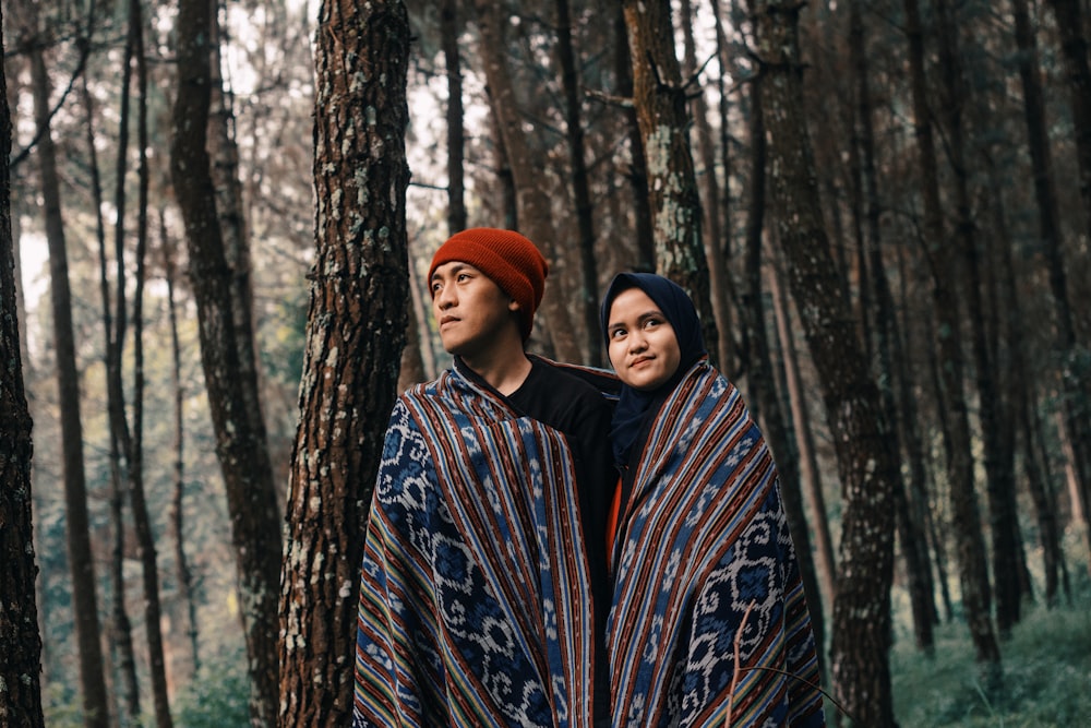 man and woman in one blanket under the woods