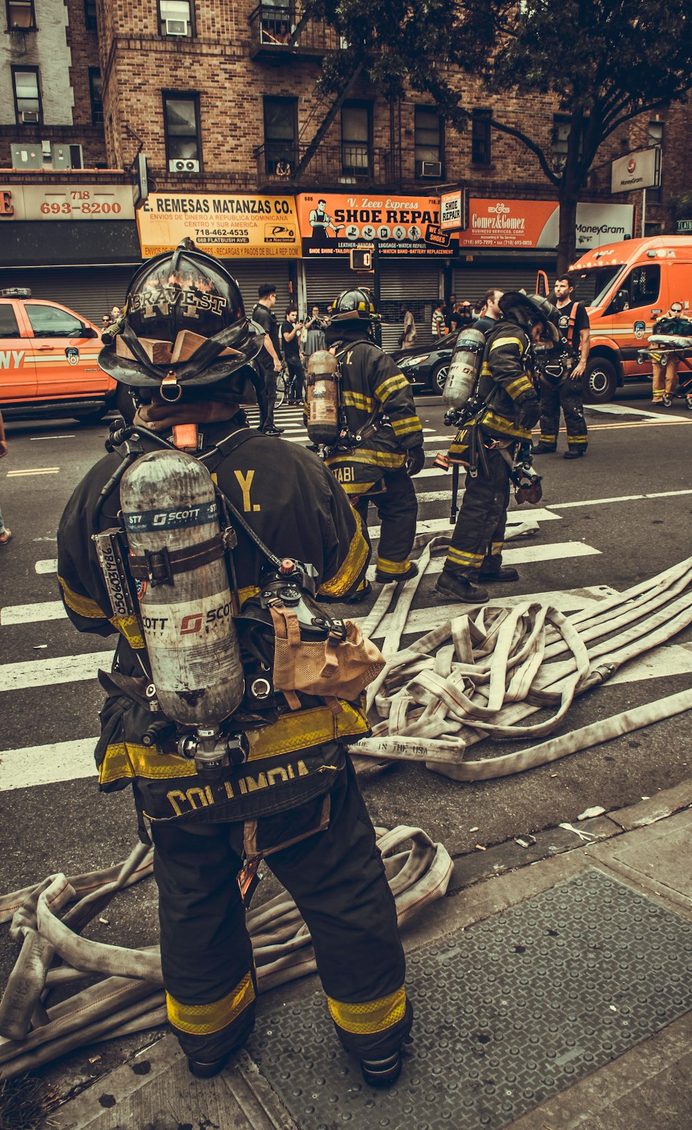 fireman holding hose standing in front of building during day time