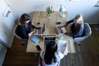 three women sitting around table using laptops