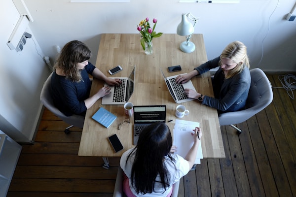 three women sitting around table using laptopsby CoWomen