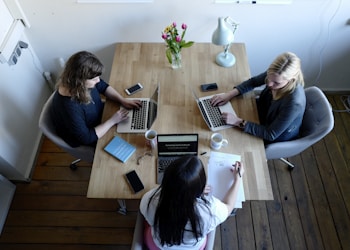 three women sitting around table using laptops