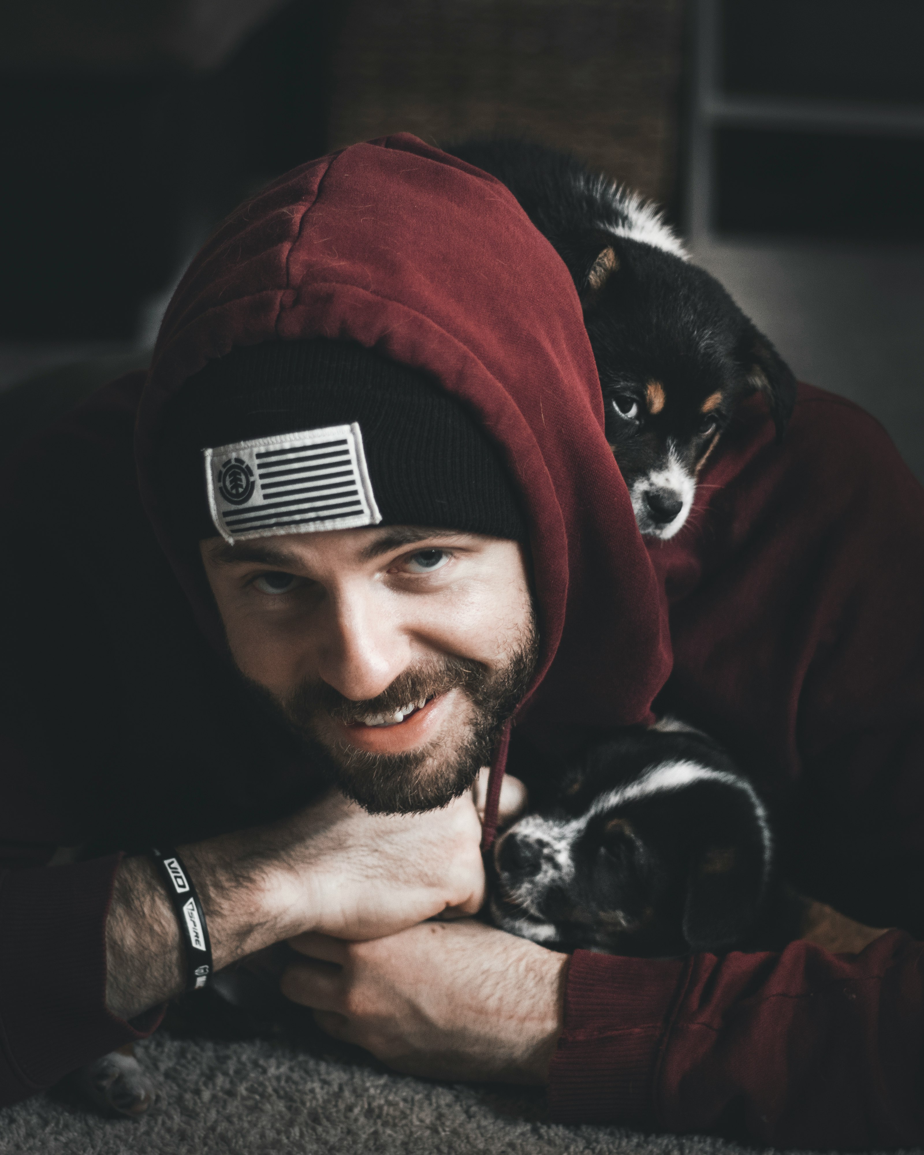 smiling man lying on floor together with black and white puppies