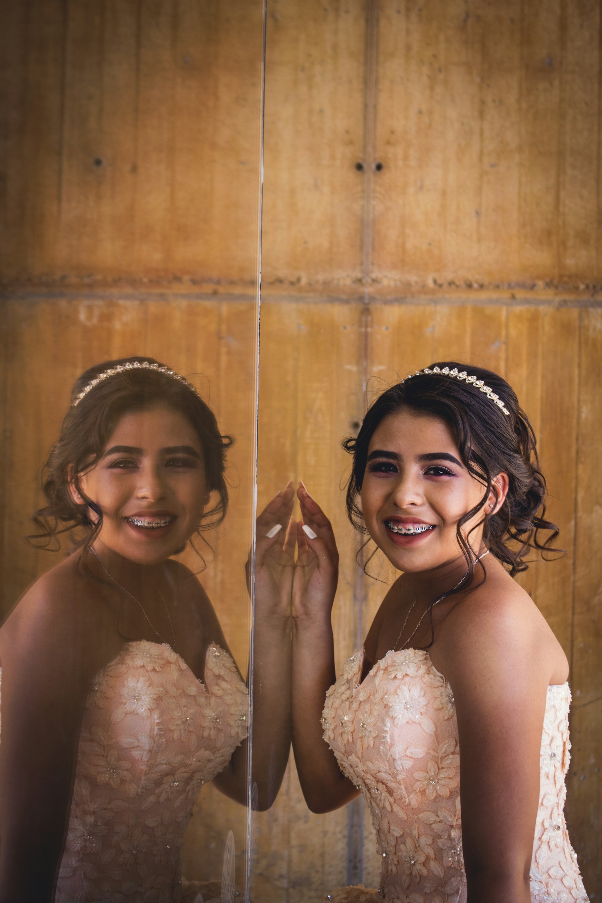Bella Ileen smiling in her elegant quinceañera dress surrounded by friends, with shimmering decorations in the background.